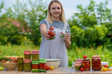 A woman preserves vegetables in jars. Selective focus. Food.