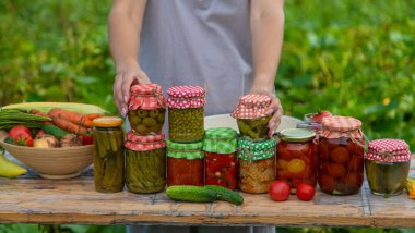 A woman preserves vegetables in jars. Selective focus. Food.