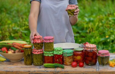 A woman preserves vegetables in jars. Selective focus. Food.