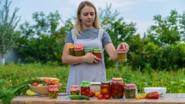 A woman preserves vegetables in jars. Selective focus. Food.