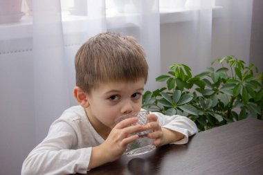 Sevimli küçük çocuk bardaktan su içiyor. Seçici odak