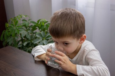 Sevimli küçük çocuk bardaktan su içiyor. Seçici odak