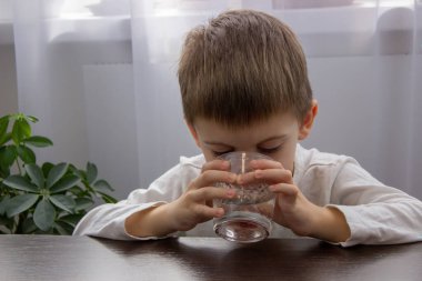 Sevimli küçük çocuk bardaktan su içiyor. Seçici odak