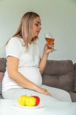 Hamile bir kadın kadehte şarap içer. Seçici odaklanma. Yiyecek..