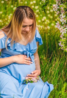 Çiçekli elma ağaçlarının bahçesinde hamile bir kadın. Seçici odaklanma. Doğa.