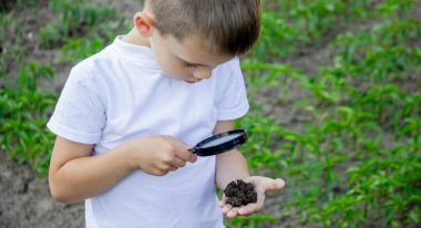 Çocuk dünyayı avucunun içinde tutuyor ve büyüteçle bakıyor. Seçici odak