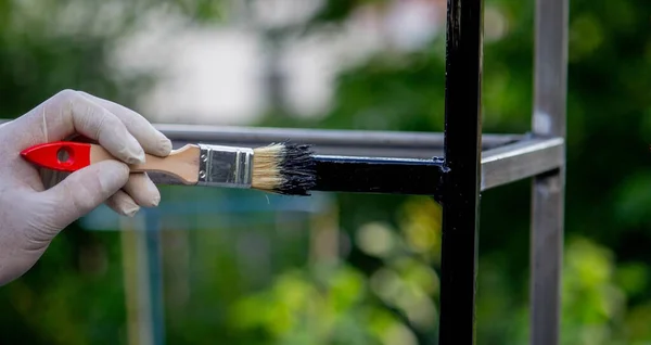 stock image a man paints metal with black paint with a brush. Selective focus