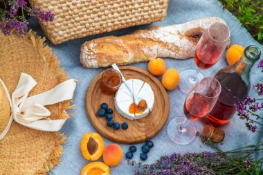 Lavanta tarlasında romantik bir piknik için lezzetli yiyeceklerle dolu bir sepet şarap, meyve, dut. Seçici odaklanma. Doğa