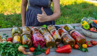 A woman preserves vegetables in jars. Selective focus. Food.