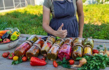 A woman preserves vegetables in jars. Selective focus. Food.