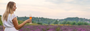 Kız lavanta tarlasında şampanya içiyor. Seçici odaklanma. Doğa