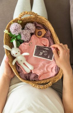 Hamile bir kadın bebek bezine ve ultrason fotoğrafına bakar. Seçici odaklanma. Şirin..