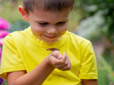 Çocuk elinde bir kelebek tutuyor. Seçici bir odak noktası. Doğa