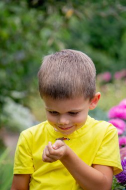 Çocuk elinde bir kelebek tutuyor. Seçici bir odak noktası. Doğa