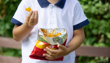 Bir çocuk parkta cips yiyor. Seçici odaklanma. Doğa
