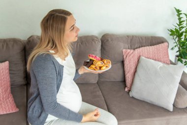 Hamile bir kadın tatlı bir çörek yer. Seçici odaklanma. Yiyecek..