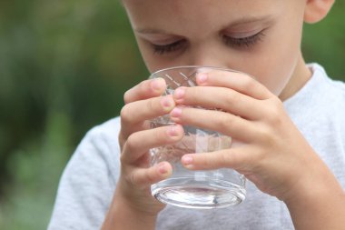 Bir çocuk doğadaki bir bardaktan su içer. Seçici odaklanma. Doğa