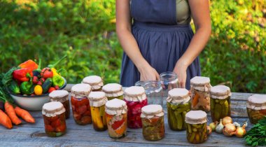 A woman preserves vegetables in jars. Selective focus. Food.