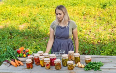 A woman preserves vegetables in jars. Selective focus. Food.