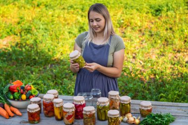 A woman preserves vegetables in jars. Selective focus. Food.