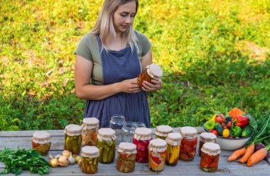A woman preserves vegetables in jars. Selective focus. Food.