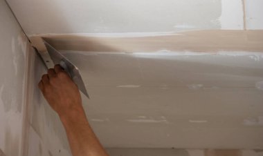 Adamın biri alçıdan tavana macun koyuyor. Plasterboard çarşafları için macun. Seçici odak