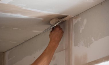 Adamın biri alçıdan tavana macun koyuyor. Plasterboard çarşafları için macun. Seçici odak