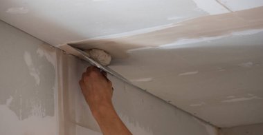 Adamın biri alçıdan tavana macun koyuyor. Plasterboard çarşafları için macun. Seçici odak