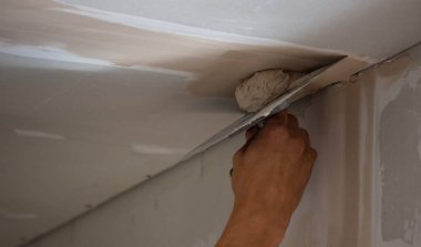 Adamın biri alçıdan tavana macun koyuyor. Plasterboard çarşafları için macun. Seçici odak