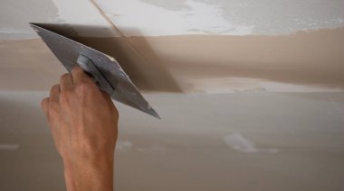 Adamın biri alçıdan tavana macun koyuyor. Plasterboard çarşafları için macun. Seçici odak