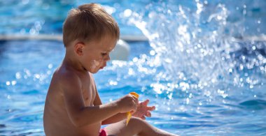 Havuz kenarındaki çocuk güneş kremi sürüyor. seçici odak