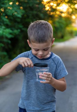 Bir çocuk büyüteçle suya bakıyor. Seçici odaklanma. Doğa