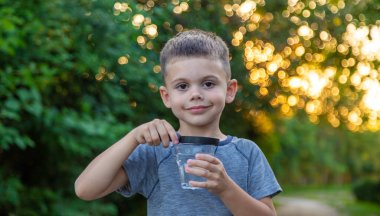 Bir çocuk büyüteçle suya bakıyor. Seçici odaklanma. Doğa
