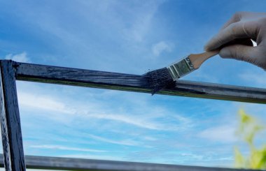 Bir adam metali siyah boyayla fırçayla boyuyor. Seçici odak