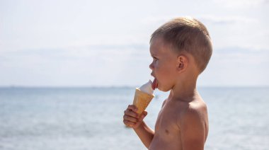 Küçük çocuk tatilde sahilde dondurma yiyor. deniz