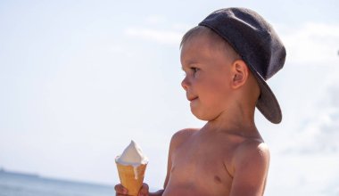 Küçük çocuk tatilde sahilde dondurma yiyor. deniz