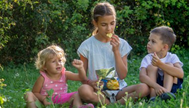 Parkta cips yiyen mutlu çocuklar. Seçici odaklanma. Bebeğim.