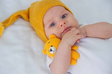 Çocuk beyaz bir arka planda küçük bir ayıyla yatıyor..