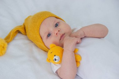 Çocuk beyaz bir arka planda küçük bir ayıyla yatıyor..