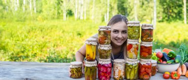 Doğanın arka planında kavanozlarda sebze konservesi konservesi yapan bir kadın. Kış için hazırlıklar.