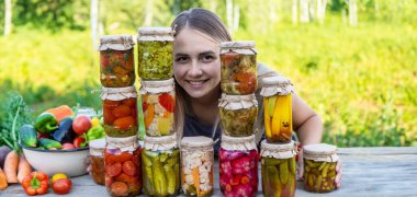 Doğanın arka planında kavanozlarda sebze konservesi konservesi yapan bir kadın. Kış için hazırlıklar.