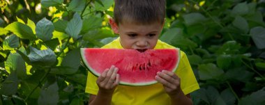 Çocuk yazın karpuz yiyor.