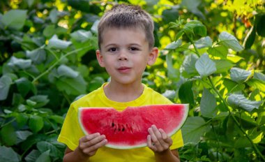 Çocuk yazın karpuz yiyor.