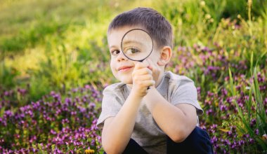 Bir çocuk büyüteçten bakar. Büyük bir çocuk gözü.