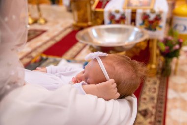 Bir kadın bir çocuğu kilisede tutuyor. Bir çocuğun vaftiz töreni. kilise
