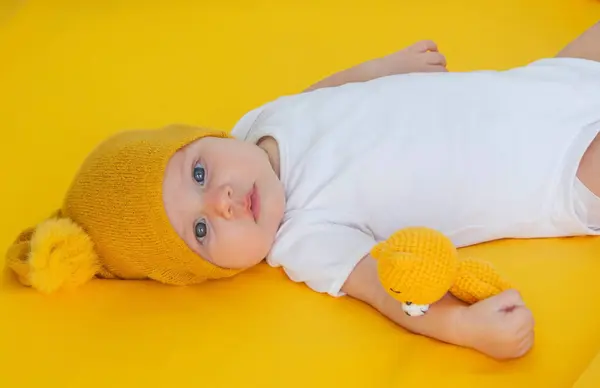 smiling baby girl goes to sleep with a teddy bear on a yellow background. children