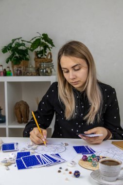 Woman astrologer draws a natal chart. Selective focus. People.