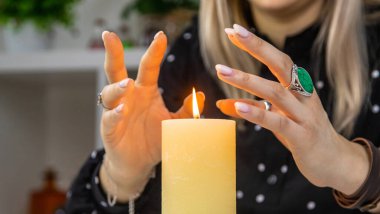 Woman fortune teller fortune telling on a candle. Selective focus. people.