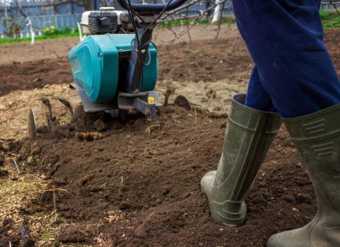 Erkek bir çiftçi tarlada bir traktörün arkasında yürüyor, tarlayı sabanla sürüyor..
