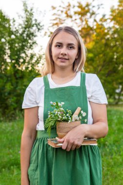 Bir kadın şifalı bitkiler toplar ve bitkisel tentürler üretir.